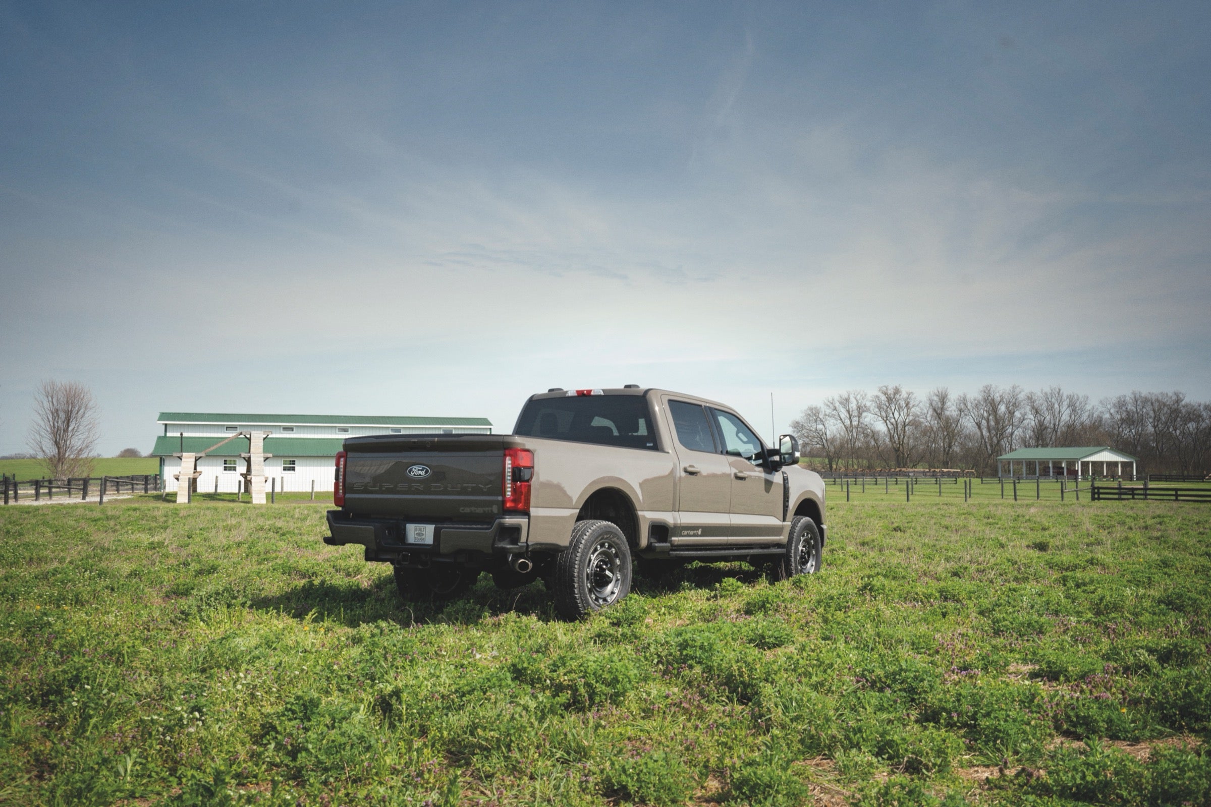 Rear three-quarter view of a 2027 Ford F-250 Super Duty parked in a farm field.