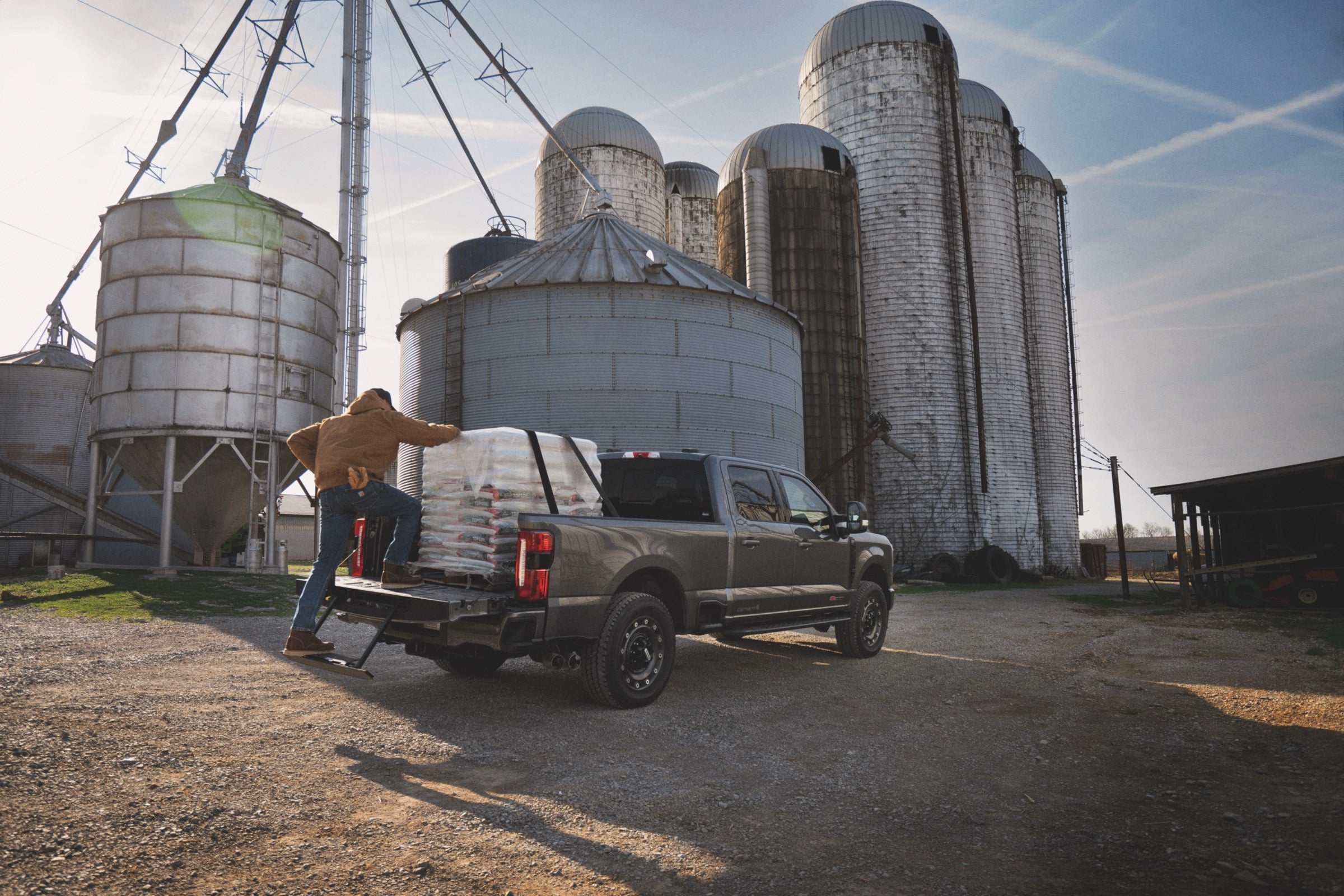 Worker loading supplies into the bed of a 2027 Ford F-350 Super Duty at a farm.