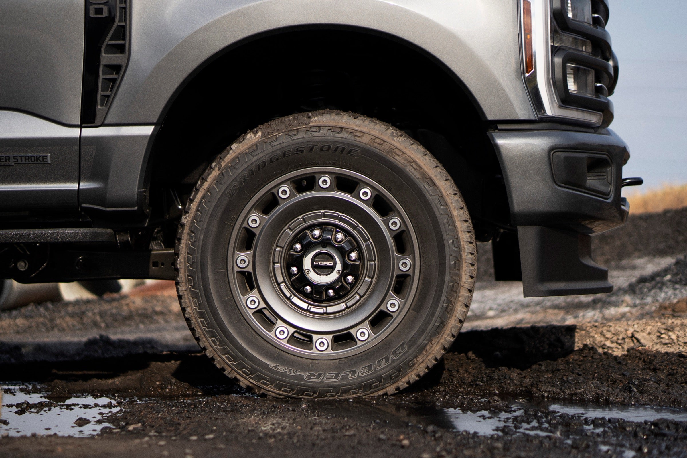 Close-up of a 2027 Ford F-350 Super Duty wheel and tire on a muddy worksite.