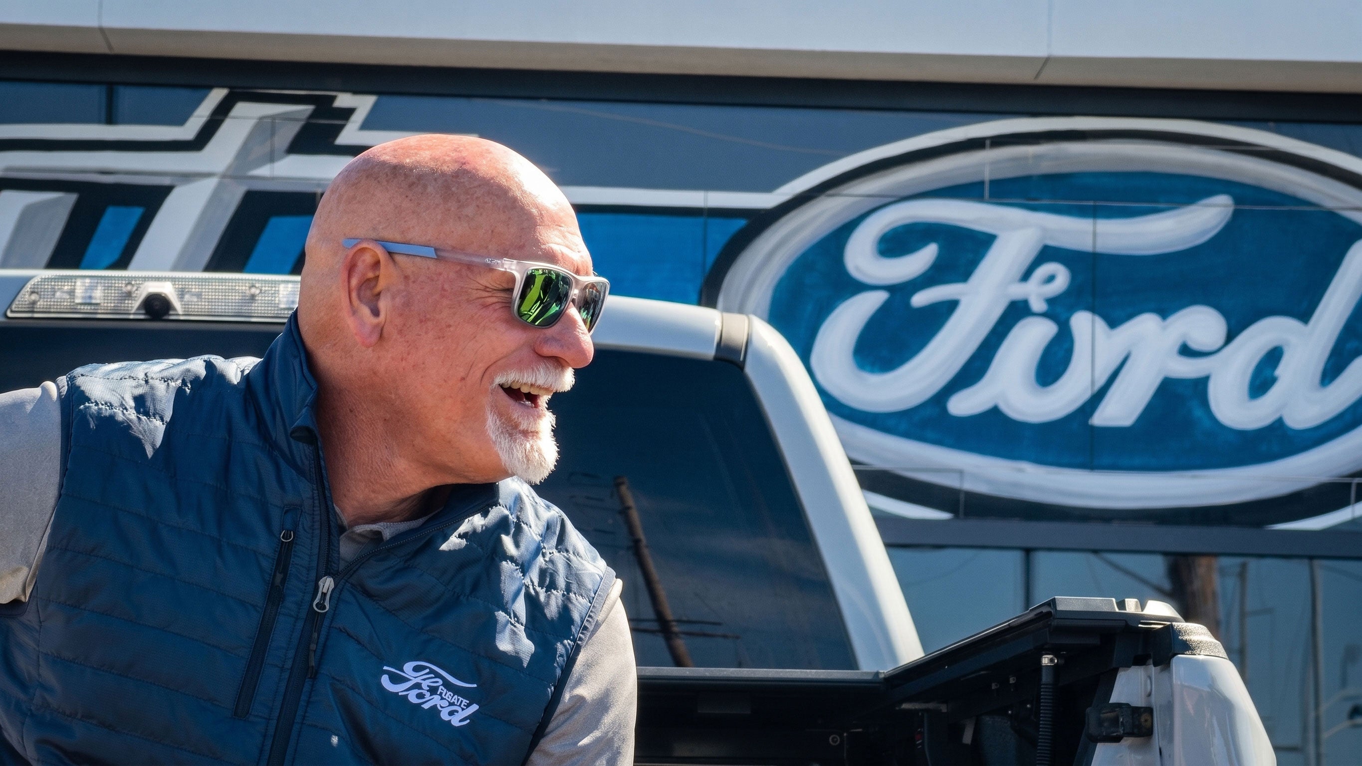 Jay Buhner smiles beside a Ford truck at Fugate Ford in Enumclaw